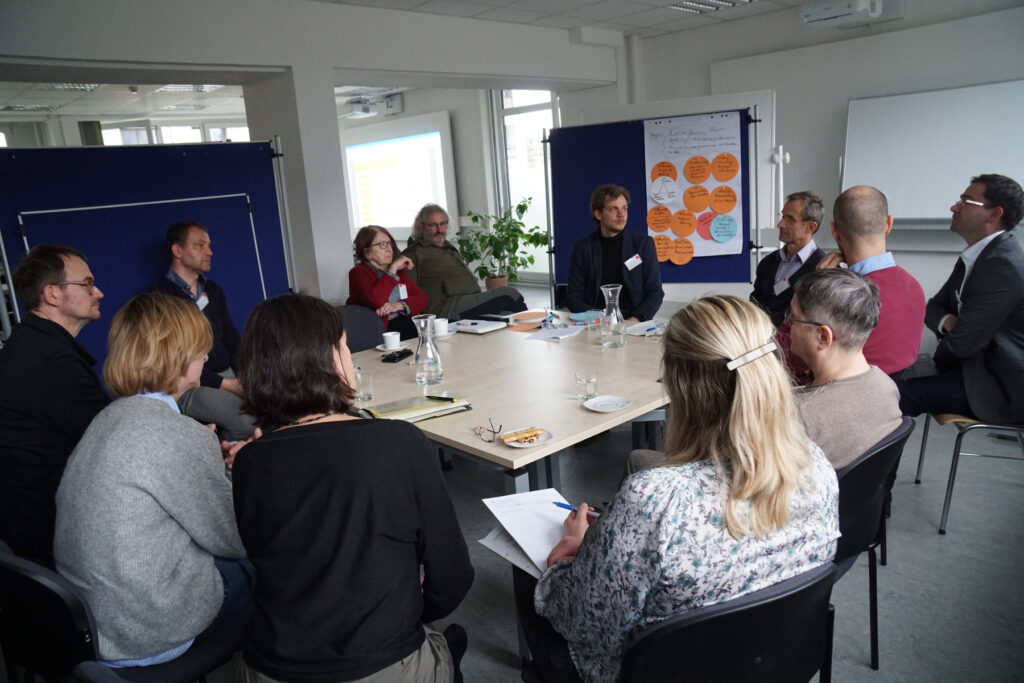 Gruppe die am Arbeitstisch diskutiert, Szene aus Workshop